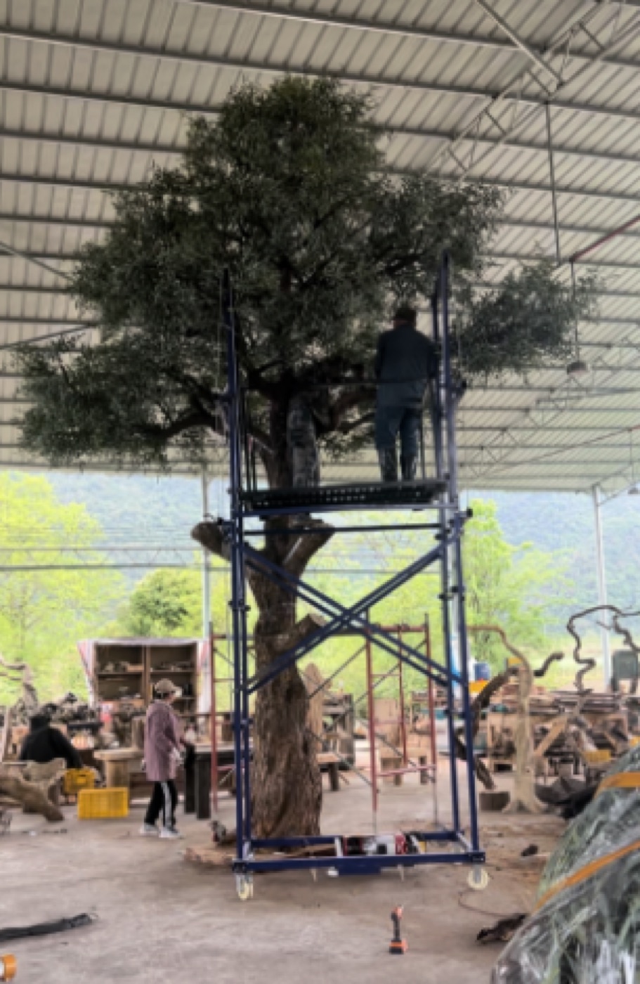 Workers raising a large tree frame on scaffolding